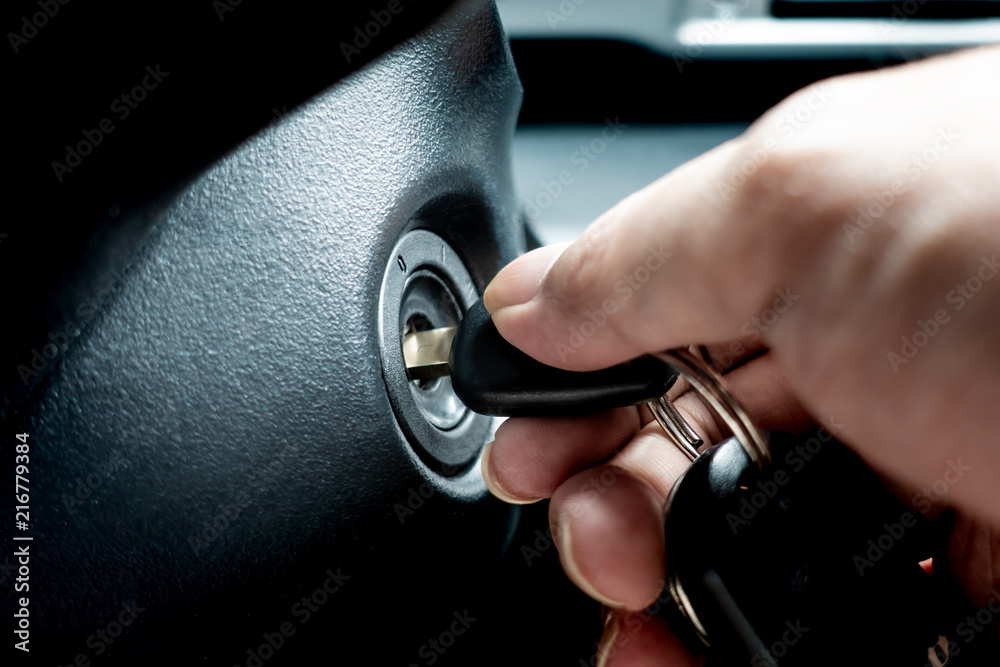 Hand turning car key in the key hole to start the car engine