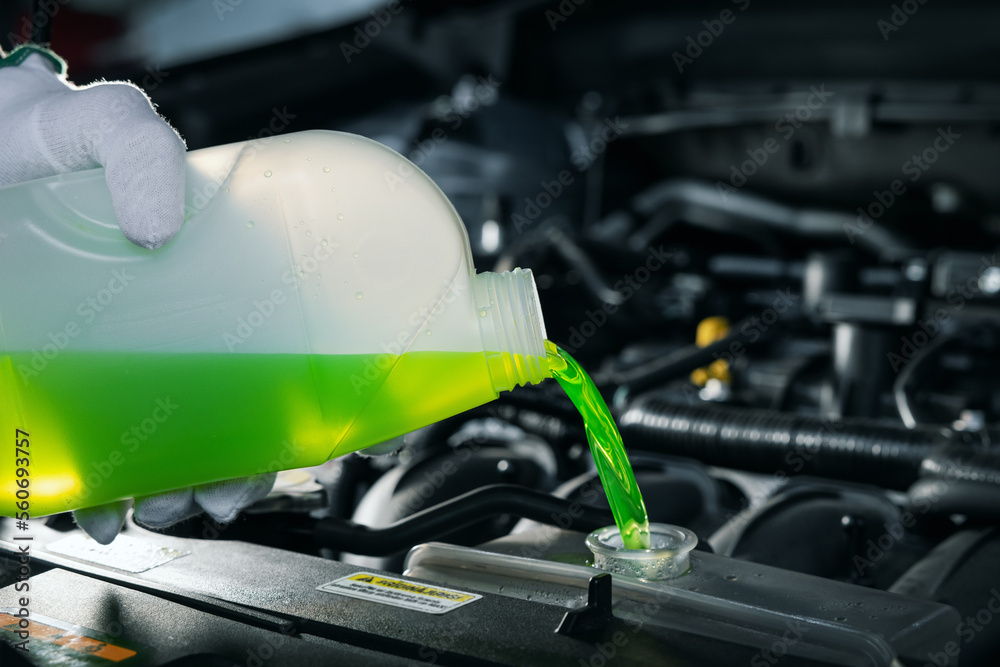pouring antifreeze coolant liquid into car engine radiator